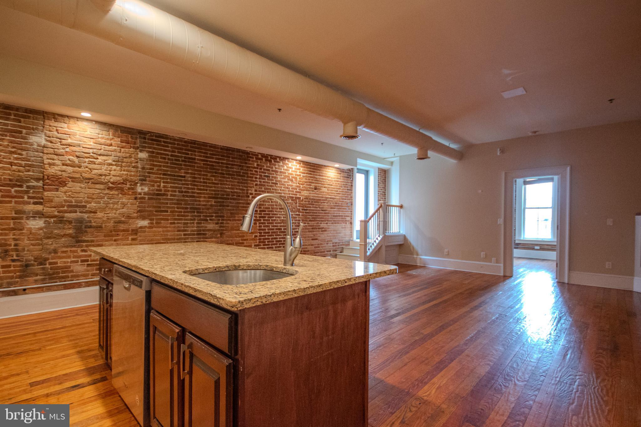 224 West Main Street, Unit 203 Salisbury, MD 21801 - Photo 6 of 20 a kitchen with stainless steel appliances granite countertop a sink dishwasher and stove with wooden floor