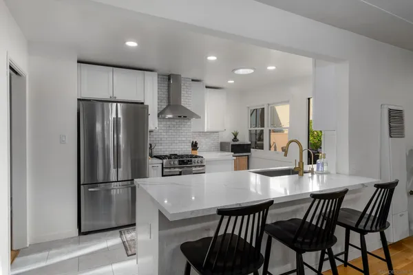 a kitchen with stainless steel appliances a refrigerator a stove a dining table and chairs