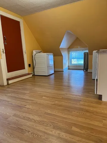 a view of an empty room with wooden floor and a cabinet