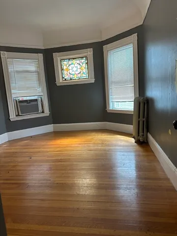 a view of an empty room with wooden floor and a window
