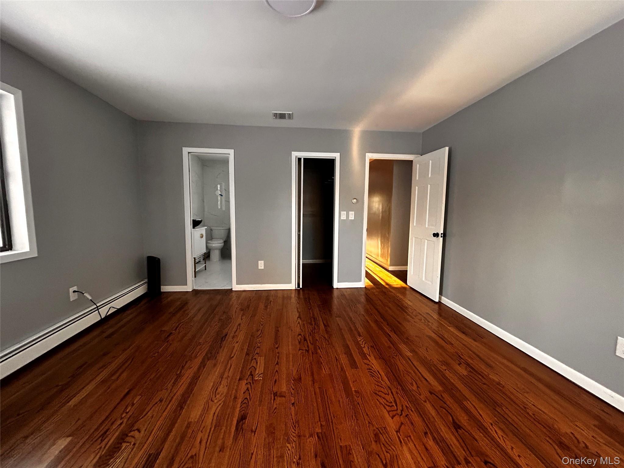 218 Beattie Road Washingtonville, NY 10992 - Photo 14 of 15 Unfurnished bedroom with a walk in closet, a baseboard heating unit, dark wood-style floors, and connected bathroom