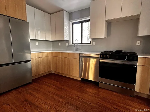 a kitchen with granite countertop wooden floors stainless steel appliances and sink