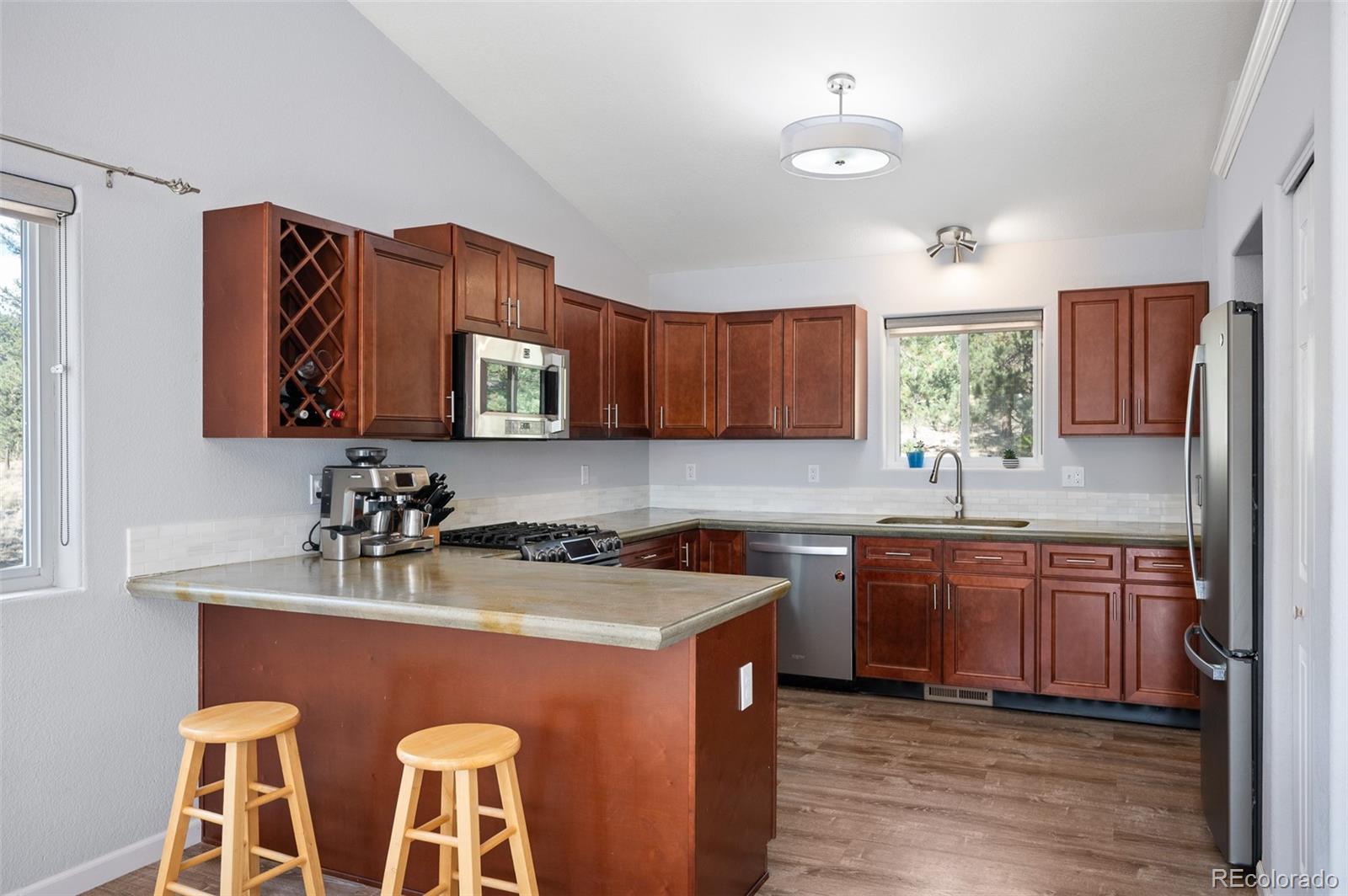 560 Gunsmoke Drive Bailey, CO 80421 - Photo 11 of 43 a kitchen with stainless steel appliances granite countertop wooden cabinets a stove top oven a sink and dishwasher