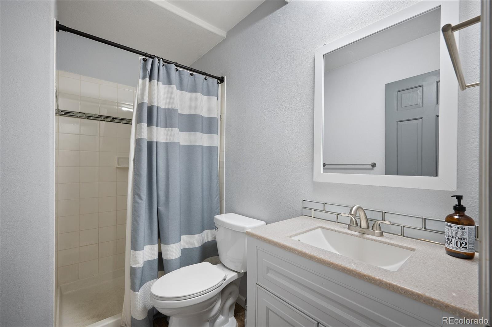 560 Gunsmoke Drive Bailey, CO 80421 - Photo 23 of 43 a bathroom with a granite countertop sink toilet a mirror and shower