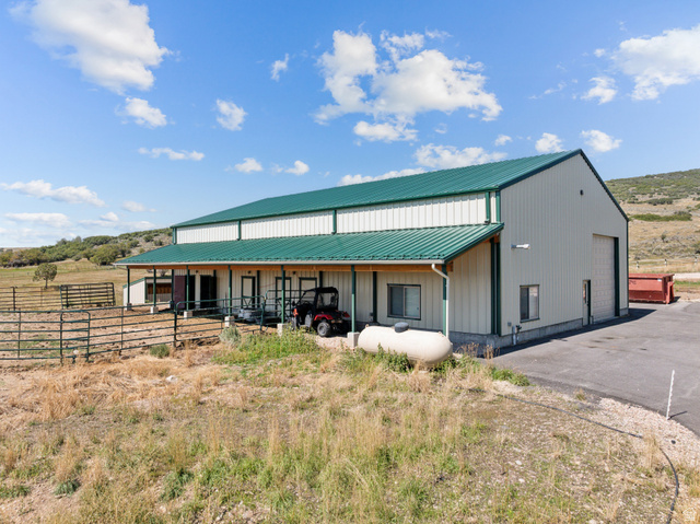 6117 North Rocky Ridge Road Peoa, UT 84061 - Photo 73 of 82 Spacious metal building featuring a vibrant green metal roof, light-colored siding, multiple entry points, and a covered porch area