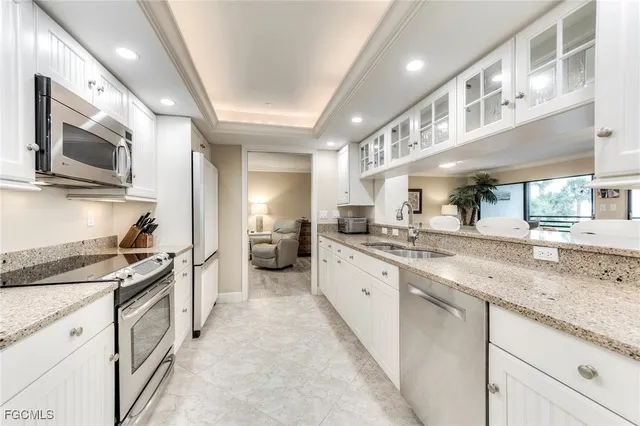 a large white kitchen with stainless steel appliances granite countertop a stove and a sink