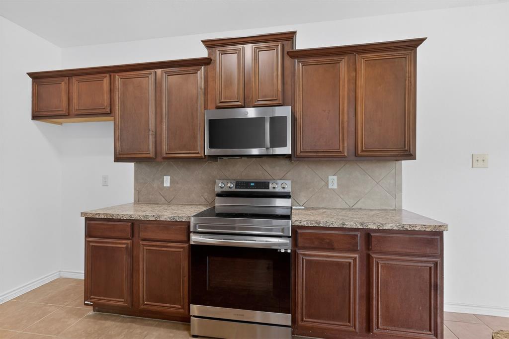 426 Harding Lane Lavon, TX 75166 - Photo 13 of 40 Kitchen featuring wood cabinetry, stainless steel oven with cooktop, built-in microwave, stone-look countertops, and a tiled backsplash
