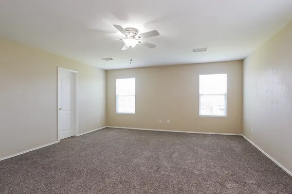 an empty room with chandelier fan and windows