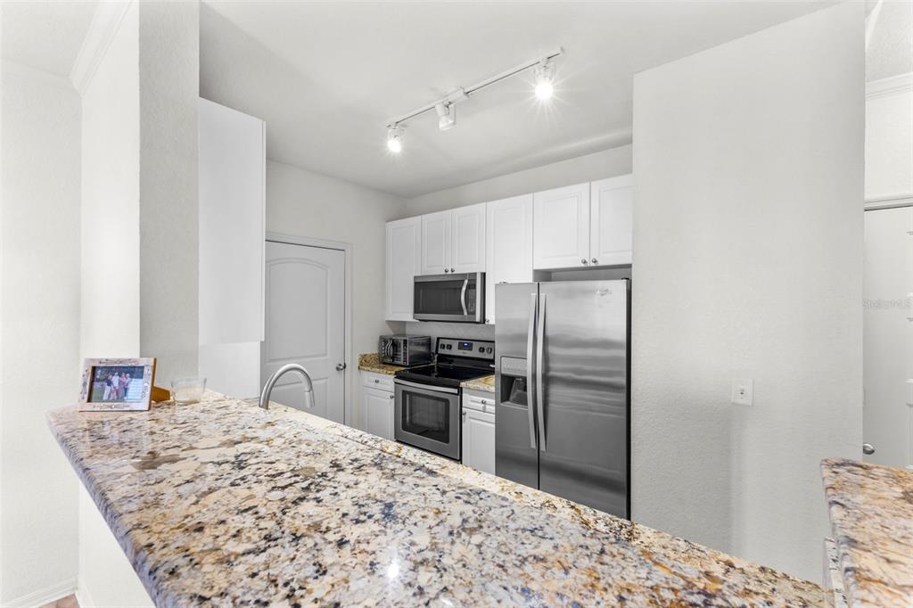 4221 West Spruce Street, Unit 1326 Tampa, FL 33607 - Photo 16 of 45 a kitchen with kitchen island a refrigerator sink stove and granite counter top