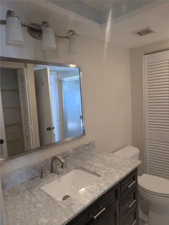 a bathroom with a granite countertop sink a toilet and mirror
