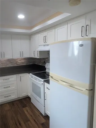 a kitchen with granite countertop white cabinets and white appliances
