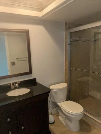 a bathroom with a granite countertop toilet sink shower and mirror