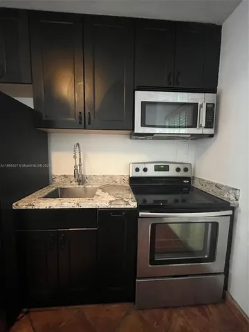 a kitchen with stainless steel appliances a stove a microwave a sink and cabinets