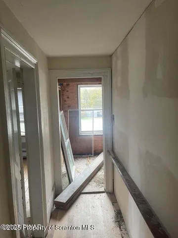 an empty room with wooden floor chandelier fan and windows