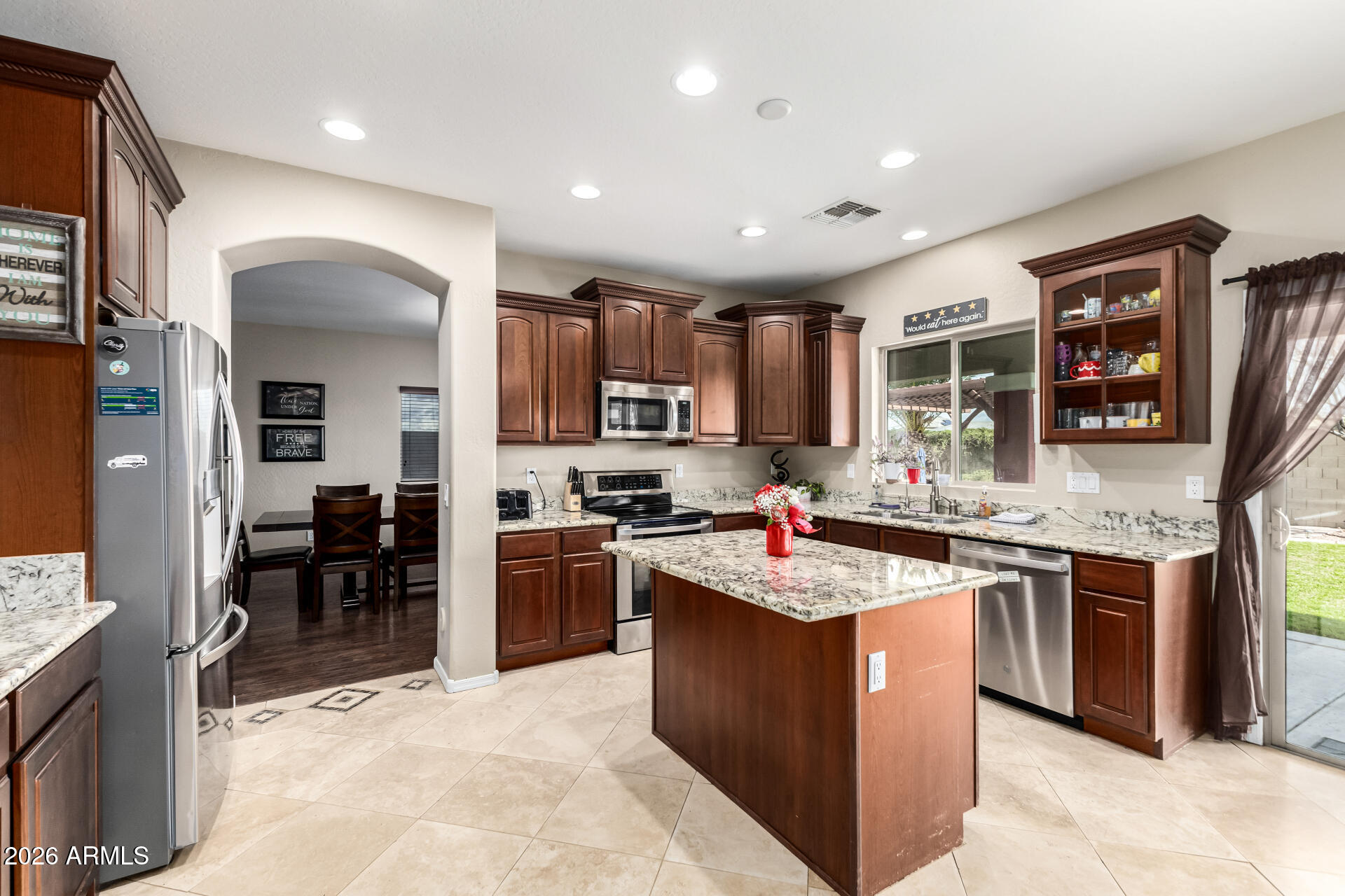 24541 Plum Road Florence, AZ 85132 - Photo 14 of 47 a kitchen with stainless steel appliances granite countertop a stove top oven a sink dishwasher a dining table and chairs