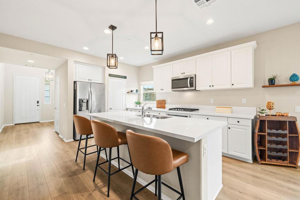 35846 Esperia Way Fallbrook, CA 92028 - Photo 11 of 60 a kitchen with stainless steel appliances granite countertop a dining table chairs stove and white cabinets