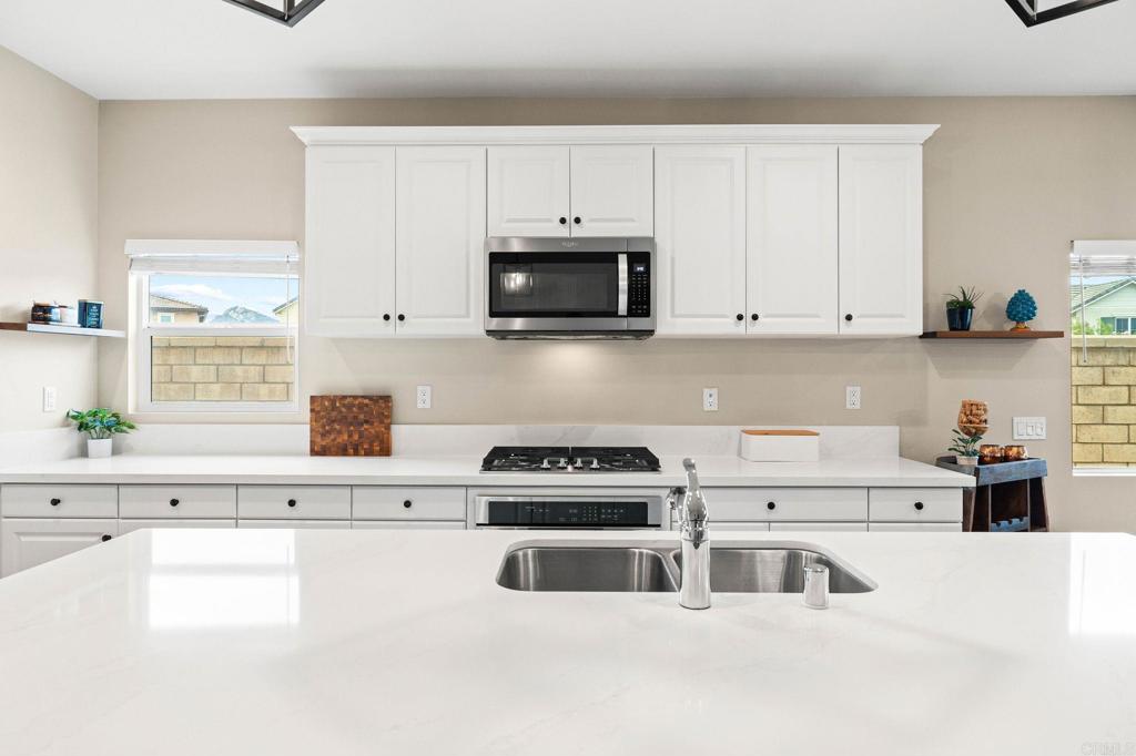 35846 Esperia Way Fallbrook, CA 92028 - Photo 13 of 60 a kitchen with white cabinets and black appliances
