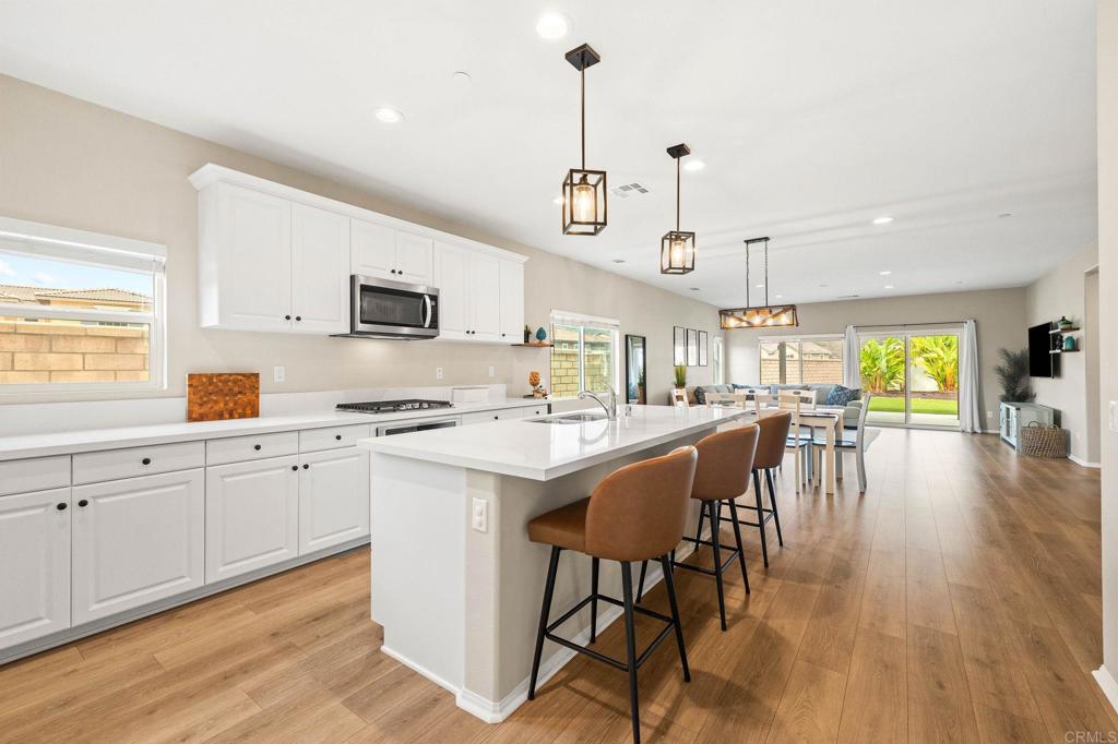 35846 Esperia Way Fallbrook, CA 92028 - Photo 10 of 60 a kitchen with stainless steel appliances granite countertop a stove top oven a sink a dining table and chairs with wooden floor