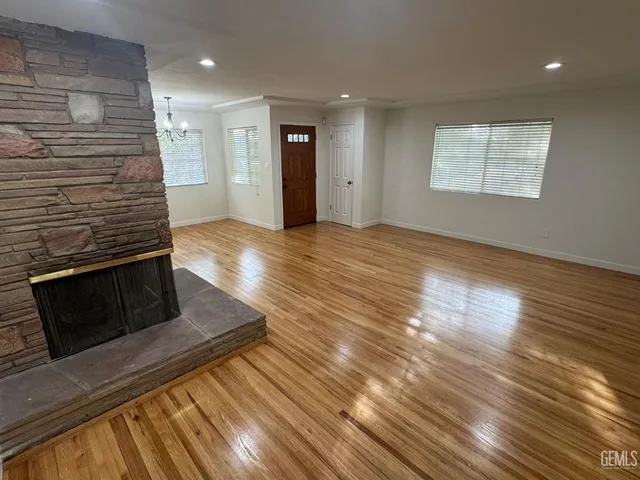 a view of an empty room with wooden floor and a fireplace
