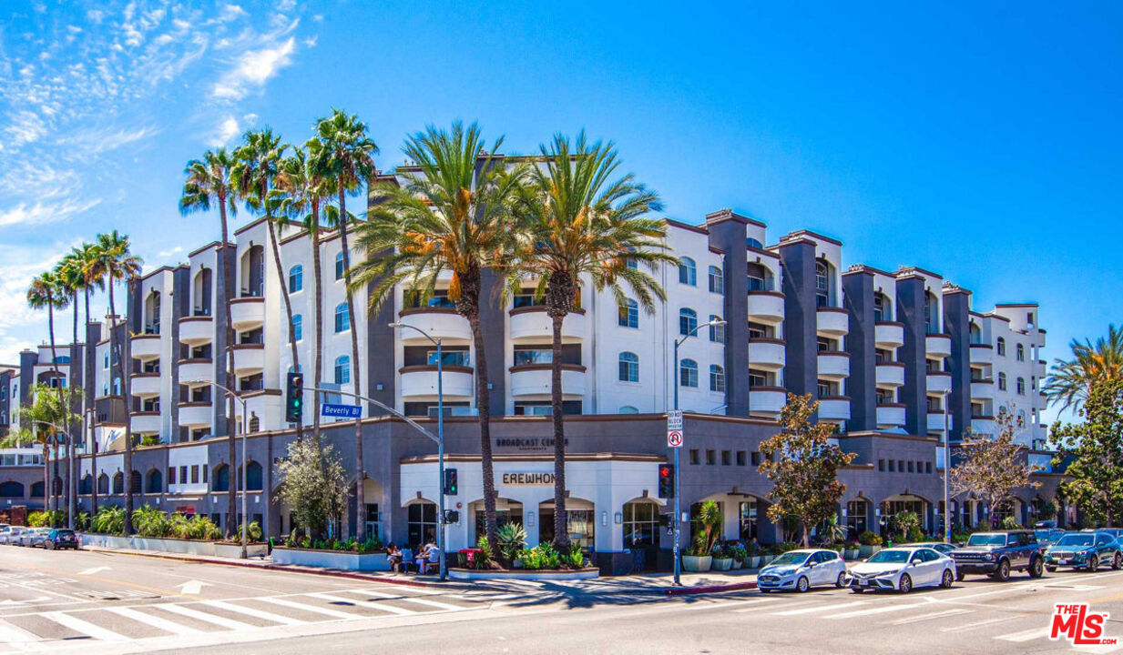 7660 Beverly Boulevard, Unit 237 Los Angeles, CA 90036 - Photo 7 of 7 a front view of multi story residential apartment building with yard and traffic signal