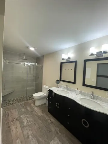 a bathroom with a granite countertop sink a toilet a mirror and shower