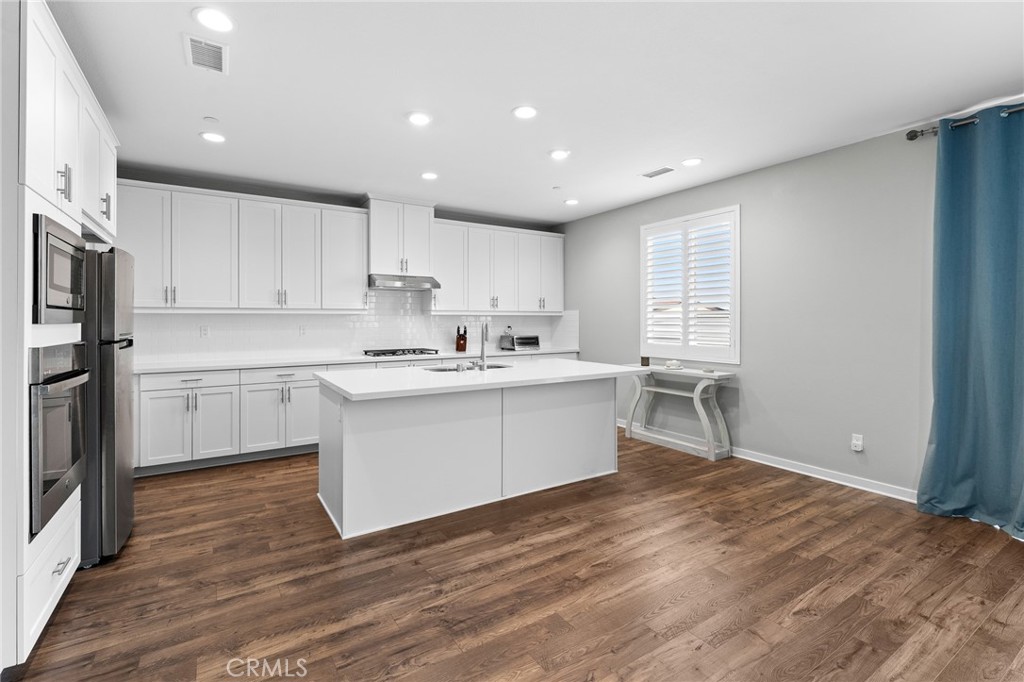 36772 Arietta Way Beaumont, CA 92223 - Photo 11 of 45 a kitchen with white cabinets and stainless steel appliances