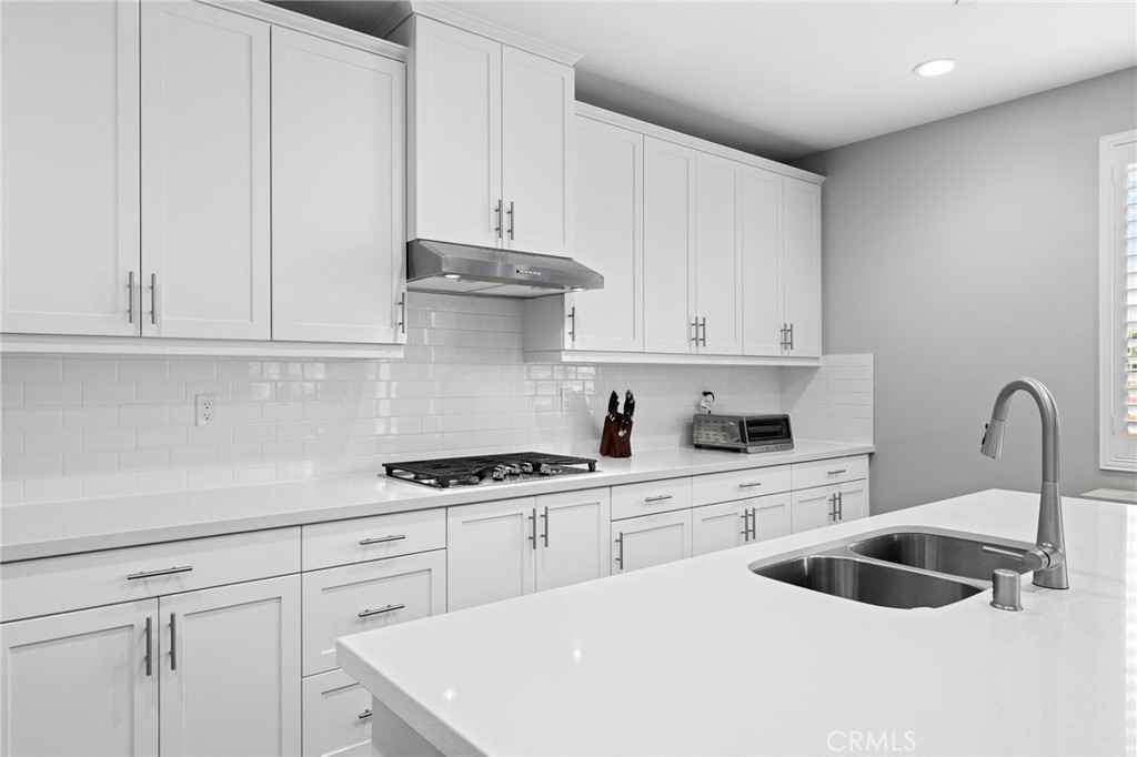 36772 Arietta Way Beaumont, CA 92223 - Photo 14 of 45 a kitchen with white cabinets a sink and white stove