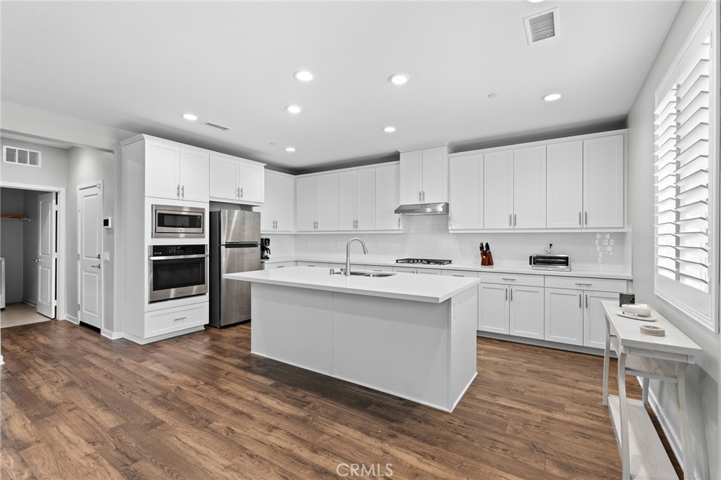 36772 Arietta Way Beaumont, CA 92223 - Photo 15 of 45 a large kitchen with kitchen island a sink a stove a refrigerator and white cabinets