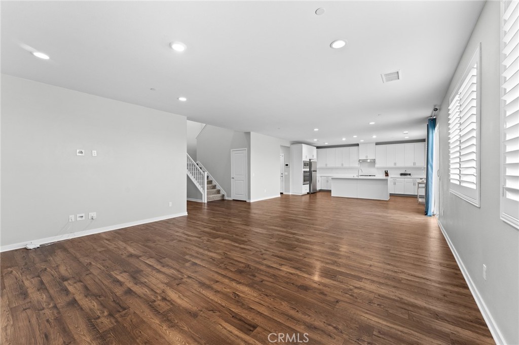 36772 Arietta Way Beaumont, CA 92223 - Photo 19 of 45 a view of empty room with wooden floor and kitchen view