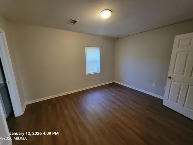 an empty room with wooden floor and window