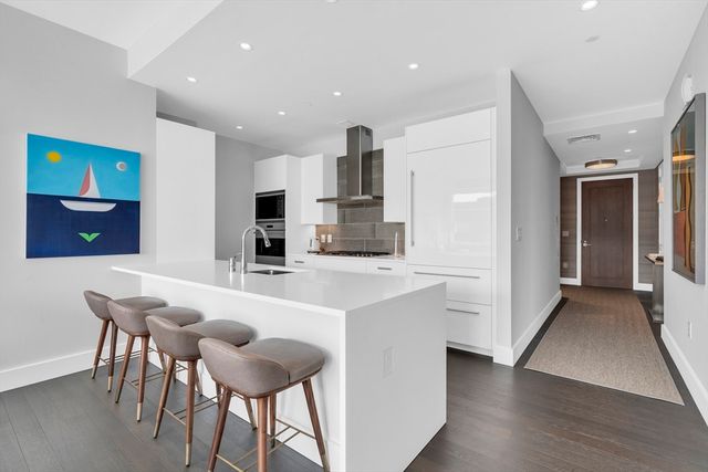 a kitchen with stainless steel appliances a dining table chairs and a refrigerator