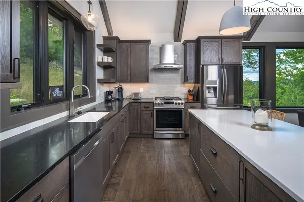 a kitchen with stainless steel appliances granite countertop a sink a stove and a wooden floors