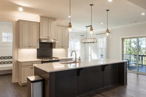 a view of a livingroom with a ceiling fan & kitchen space