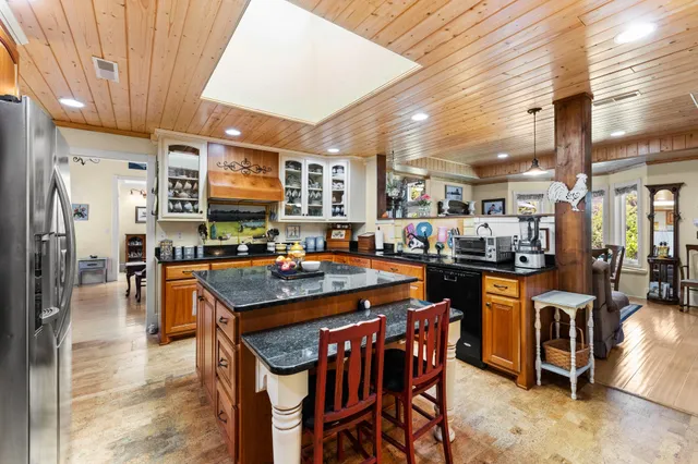 a dining hall with stainless steel appliances kitchen island granite countertop a dining table and chairs