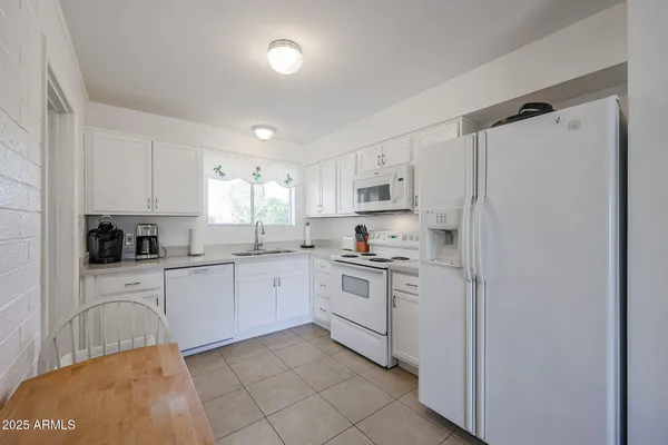 a kitchen with white cabinets and white appliances