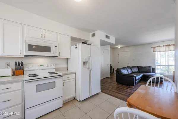 a kitchen with stainless steel appliances granite countertop a stove a sink dishwasher a refrigerator and a microwave oven with white cabinets