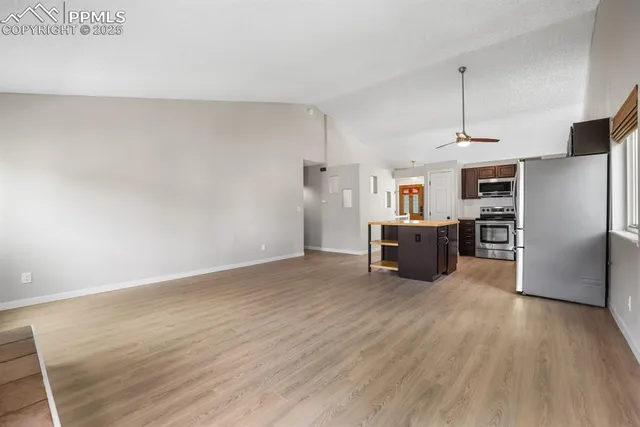 a kitchen with stainless steel appliances a refrigerator and a wooden floor
