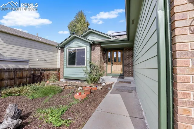 a view of a house with a small yard and floor to ceiling window and wooden fence