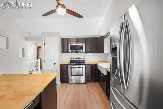 a kitchen with stainless steel appliances granite countertop a refrigerator a stove and a sink
