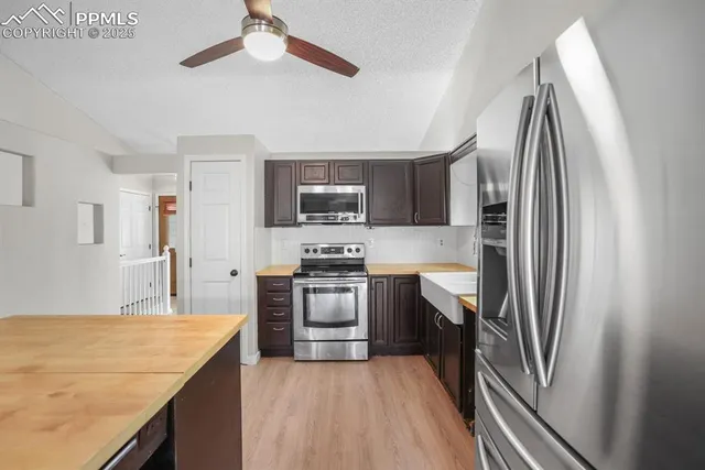 a kitchen with stainless steel appliances granite countertop a refrigerator a stove and a sink