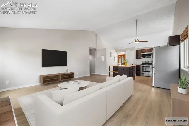 a living room with stainless steel appliances furniture and a flat screen tv