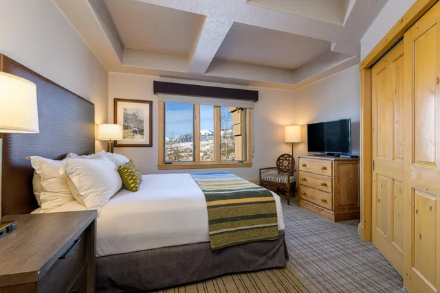 a bedroom with a bed and a flat screen tv on dresser