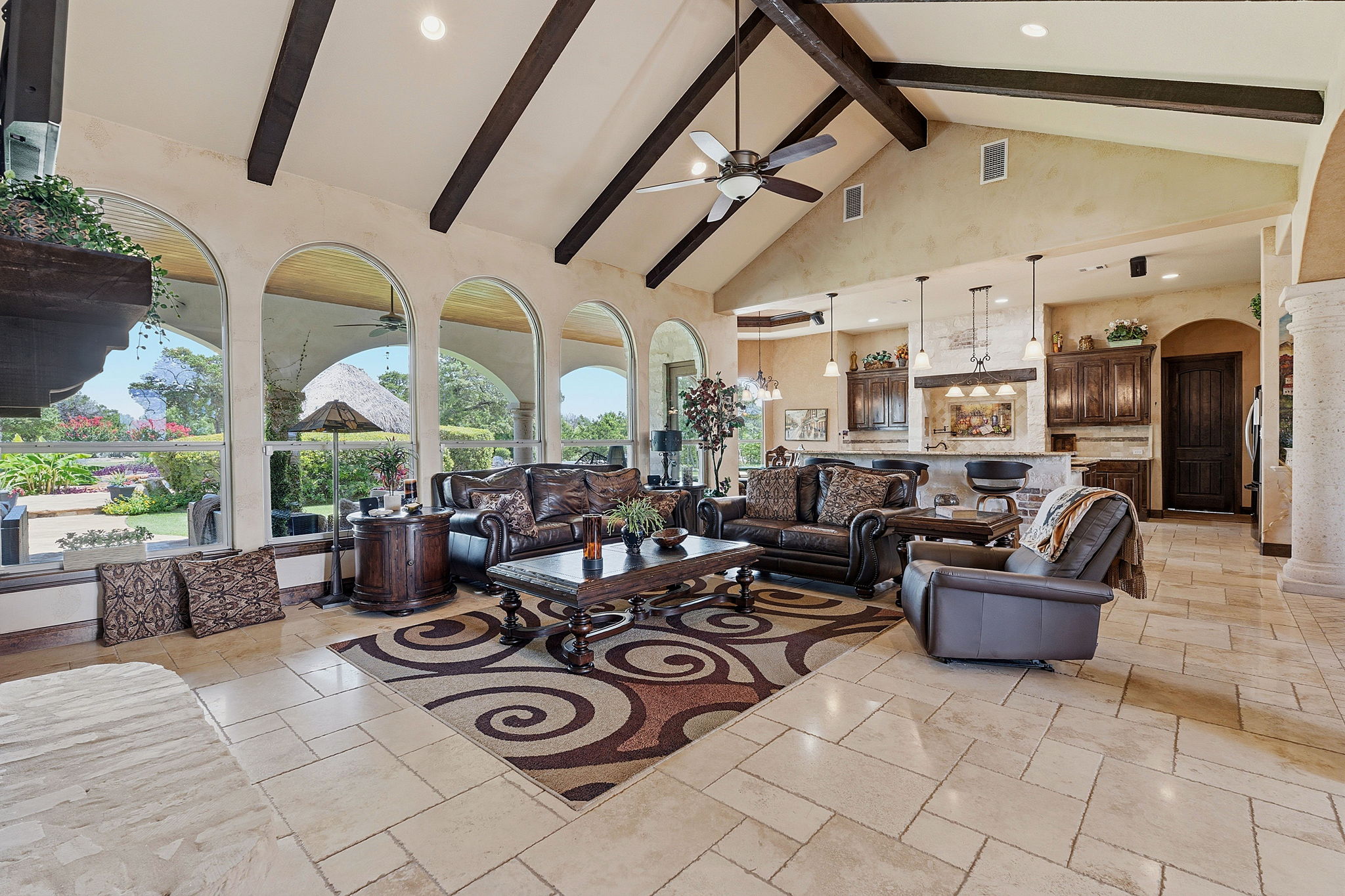 816 Brave Face Street Leander, TX 78641 - Photo 3 of 40 Arched windows frame vibrant garden views in this open-concept living space with vaulted ceilings and exposed beams.