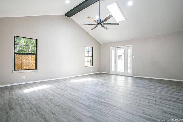 a view of an empty room with wooden floor and a window