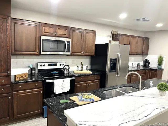 a kitchen with stainless steel appliances granite countertop a stove refrigerator sink and microwave