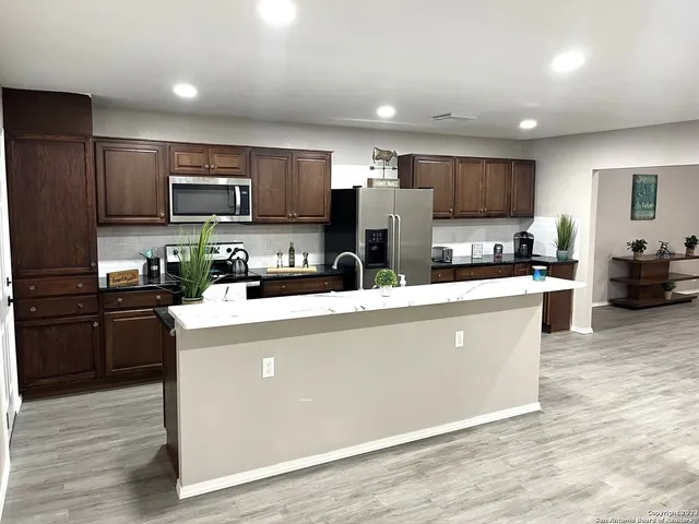 a kitchen with stainless steel appliances a sink a stove a microwave a refrigerator a sink and a refrigerator