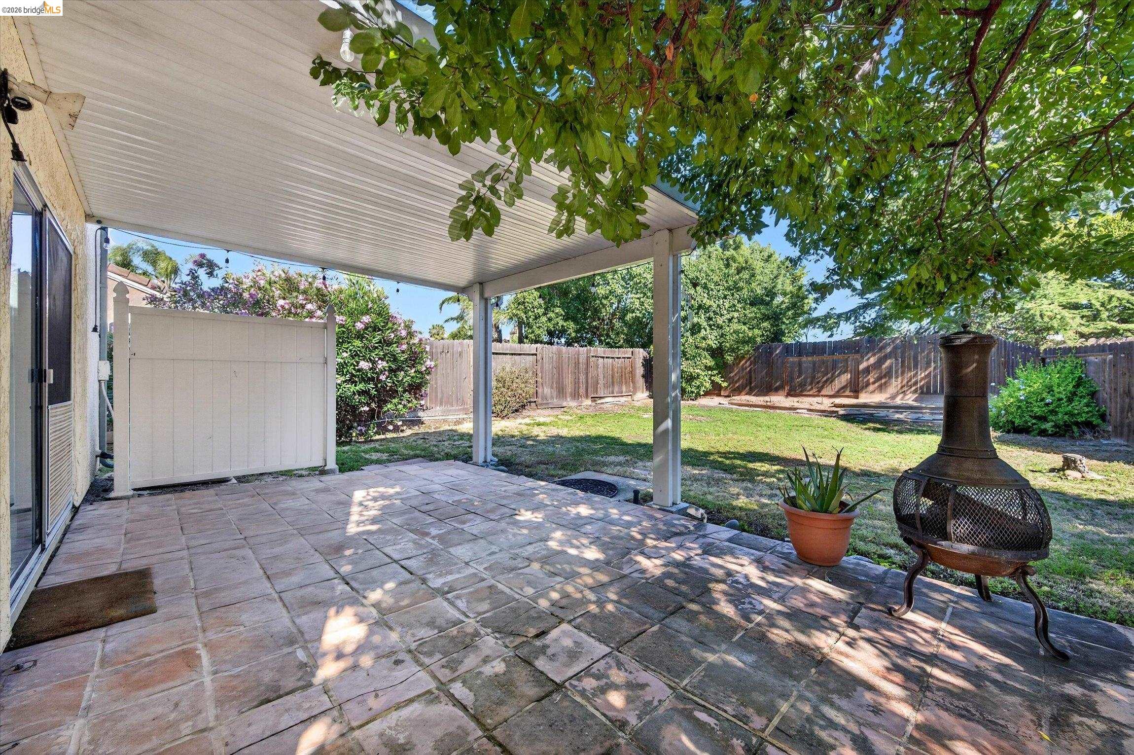 1120 Deerpark Road Oakley, CA 94561 - Photo 28 of 30 Covered patio with large format pavers, providing access to a fenced backyard with mature trees and a manicured lawn