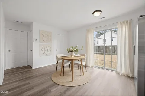 a dining room with wooden floor a chandelier a glass table and chairs