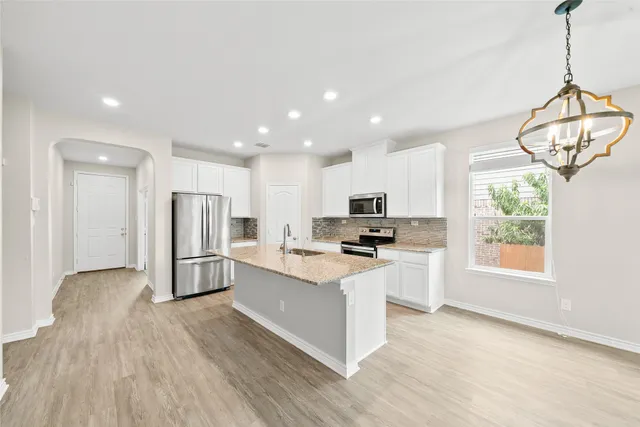 a kitchen with stainless steel appliances a stove top oven a sink a refrigerator a window and white cabinets