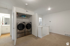 Dedicated laundry closet with built-in shelving, front-loading washer and dryer, and adjacent bathroom